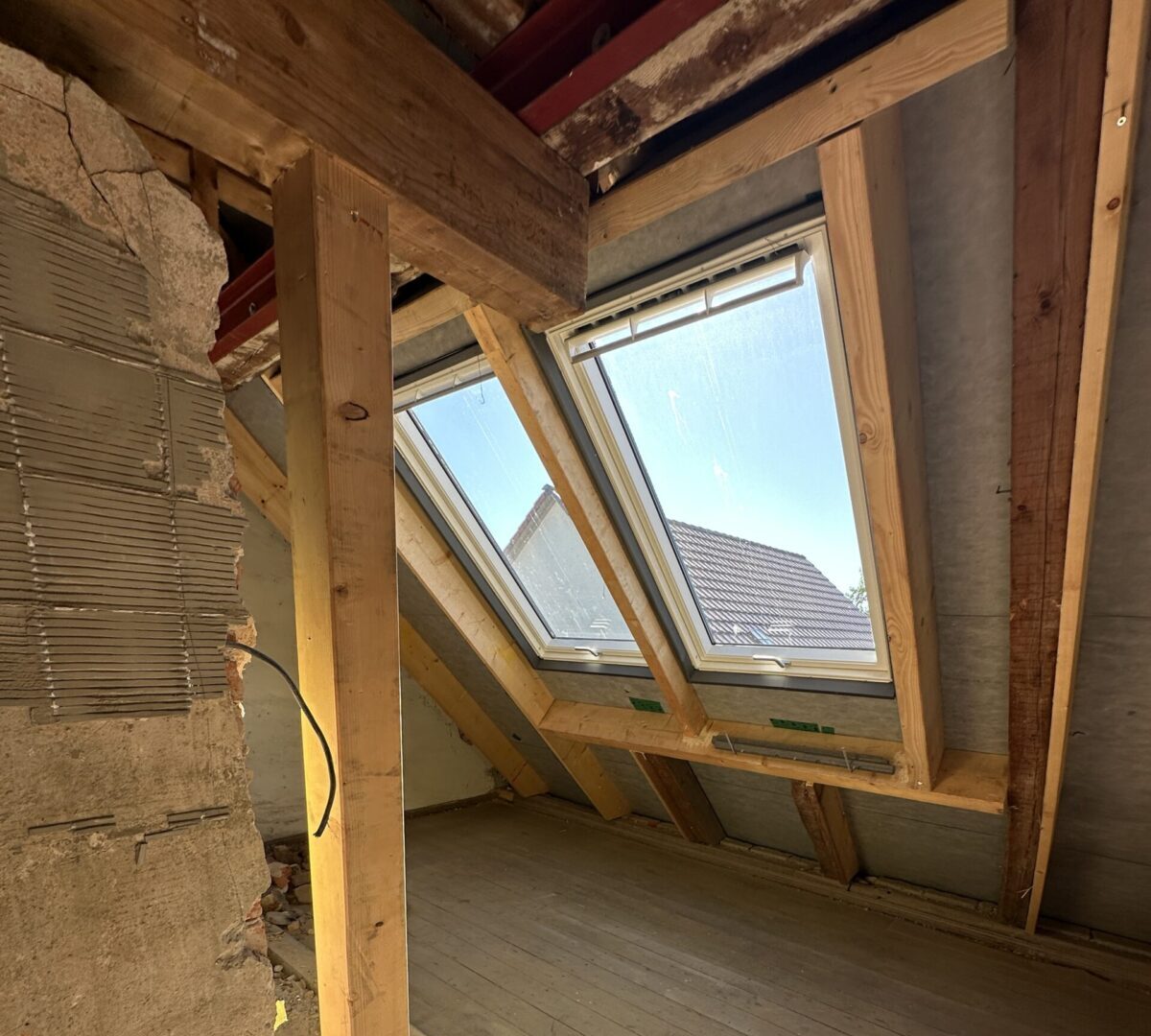 Sanierungsarbeiten am Dachgeschoss des Katzenhauses Innenaufnahme eines Dachbodens mit neuen Dachfenstern und sichtbaren Holzbalken während der Sanierungsarbeiten
